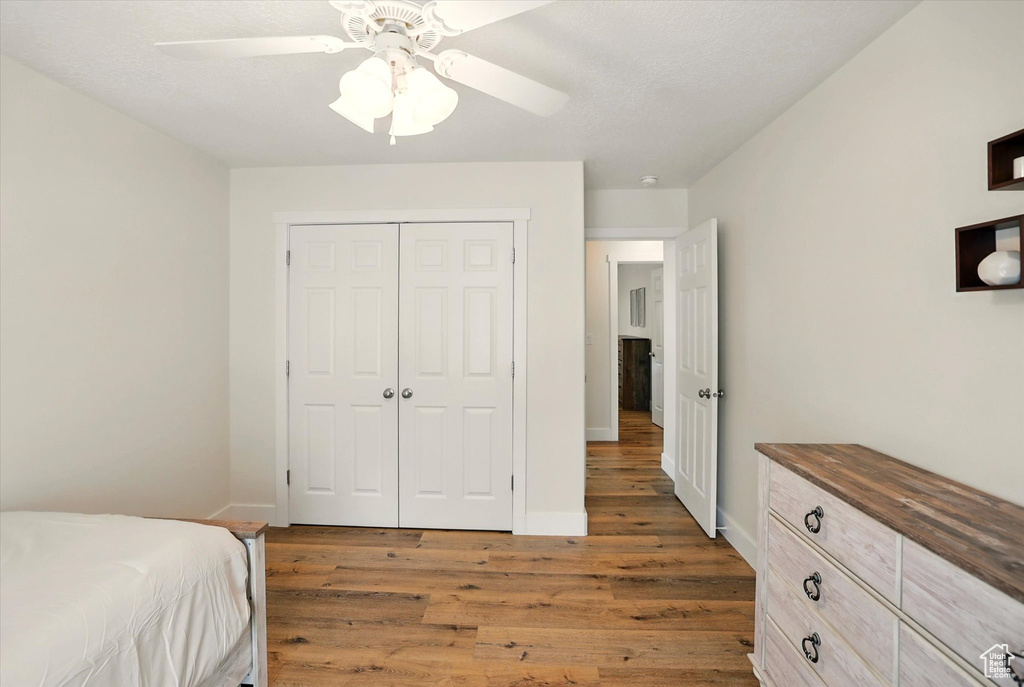 Bedroom featuring wood finished floors, a closet, baseboards, and ceiling fan