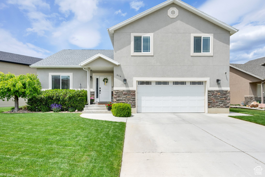 View of front of property with stucco siding, a front yard, concrete driveway, and a garage