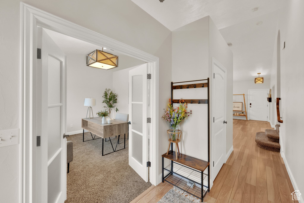 Hallway featuring light wood finished floors, baseboards, and an office area