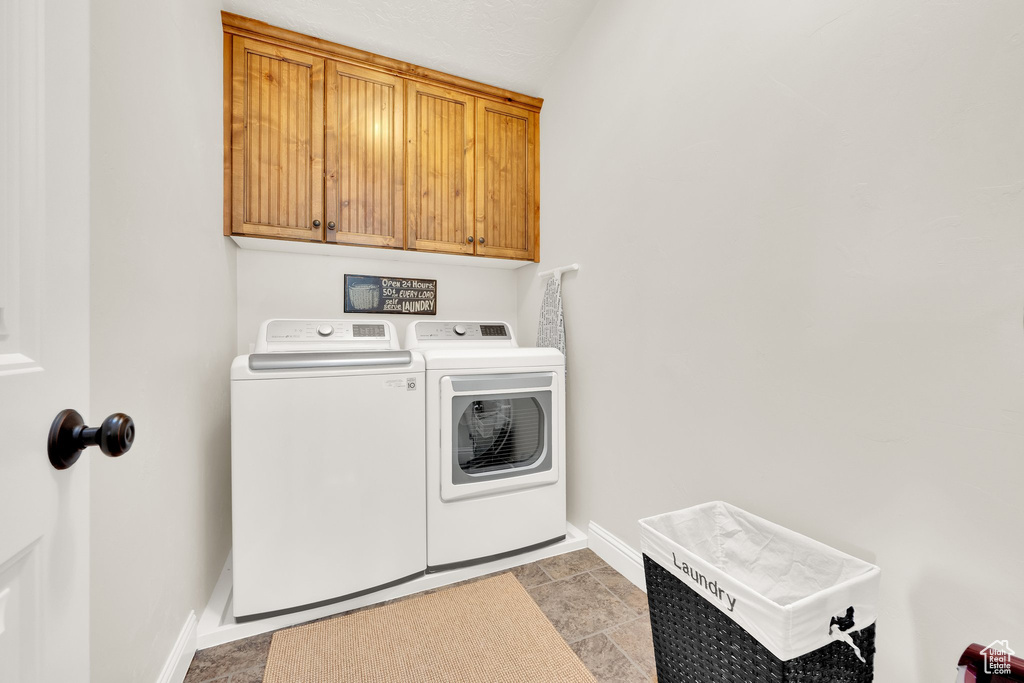 Laundry area featuring independent washer and dryer, cabinet space, and baseboards