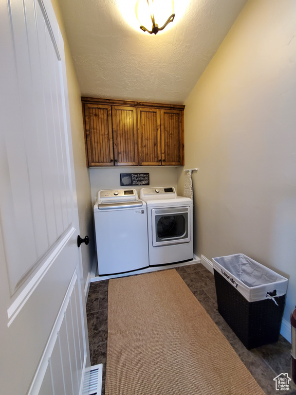 Laundry area featuring cabinet space, washer and dryer, a textured ceiling, and baseboards
