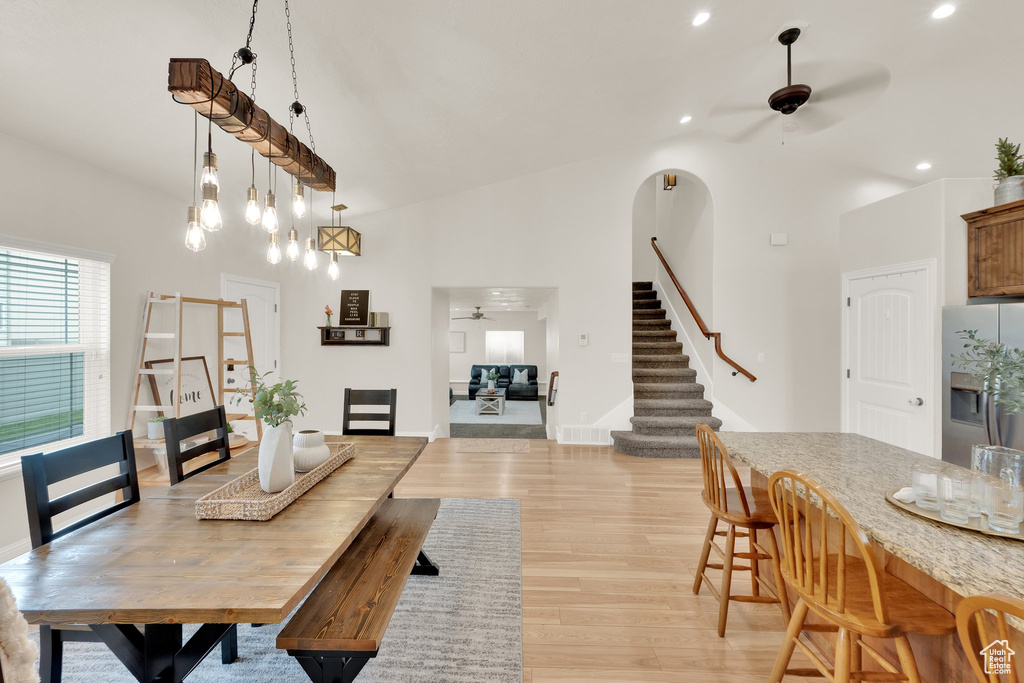Dining space with a ceiling fan, high vaulted ceiling, stairway, light wood-style floors, and recessed lighting
