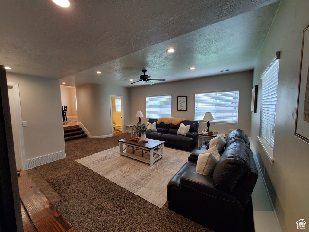 Living area featuring recessed lighting, stairs, carpet, ceiling fan, and a textured ceiling