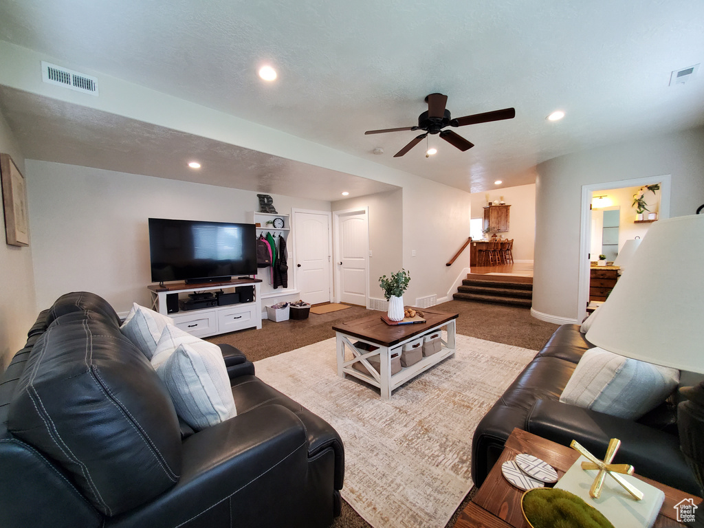 Carpeted living area with recessed lighting, stairway, ceiling fan, and baseboards