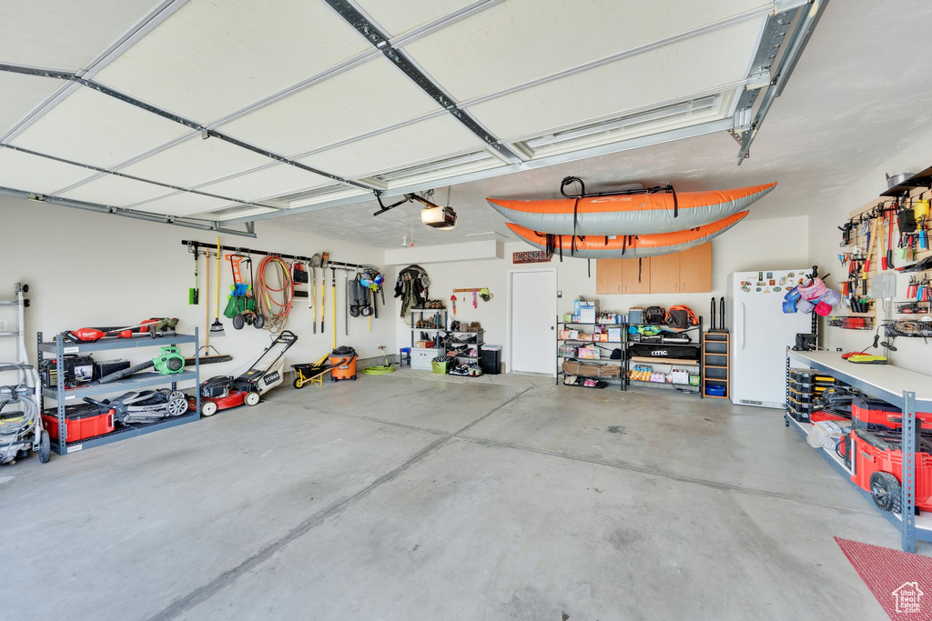 Garage with freestanding refrigerator, a garage door opener, and a workshop area