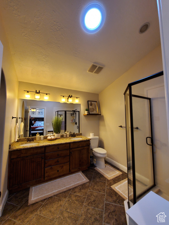 Bathroom featuring ensuite bath, baseboards, a stall shower, toilet, and double vanity