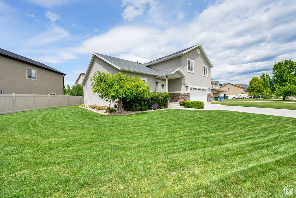 View of front facade with stucco siding, a garage, driveway, and stone siding