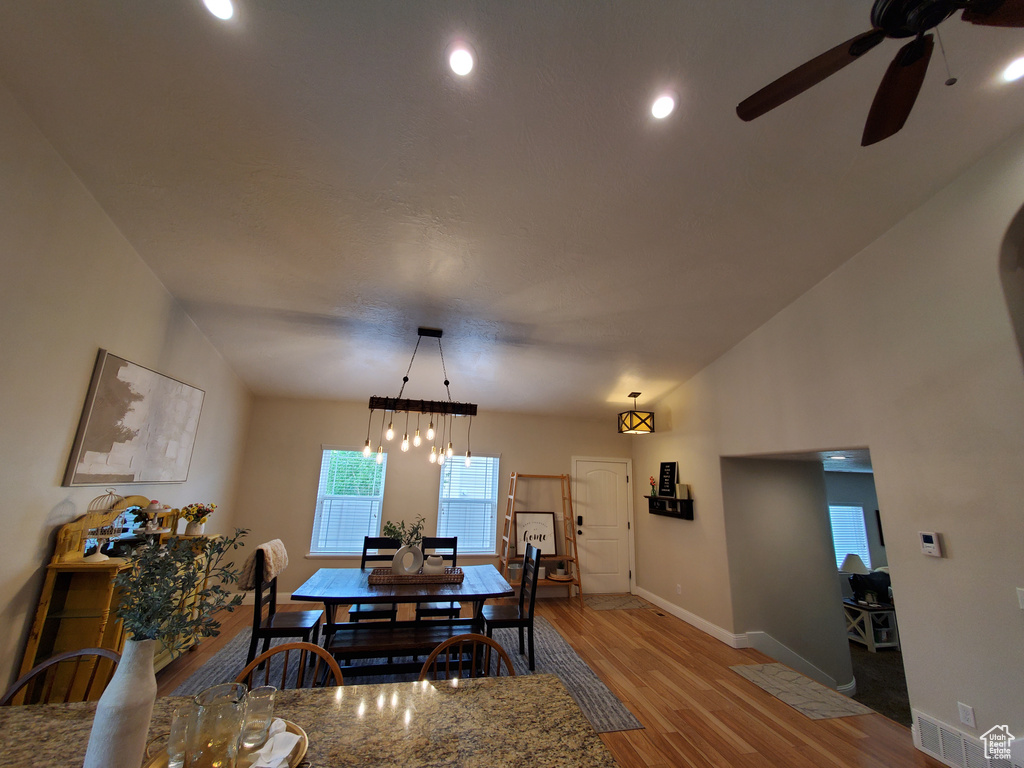 Dining area with a ceiling fan, wood finished floors, baseboards, recessed lighting, and a chandelier