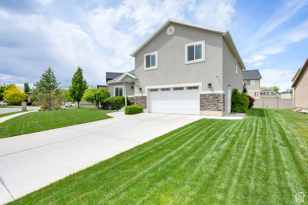 View of front facade with a garage, stone siding, concrete driveway, and stucco siding