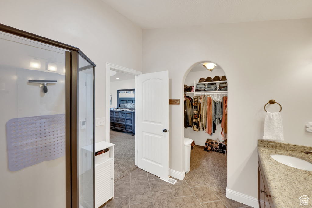 Bathroom featuring a stall shower, vanity, a spacious closet, tile patterned floors, and baseboards