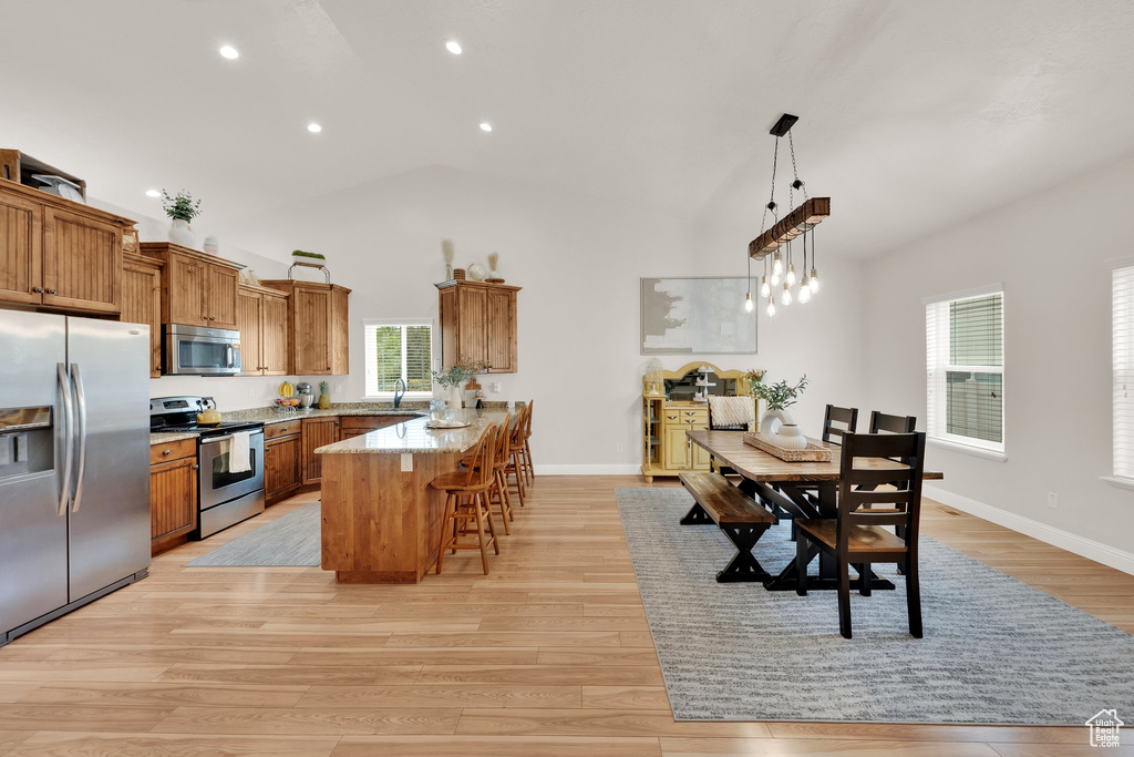 Kitchen featuring stainless steel appliances, brown cabinetry, a peninsula, a kitchen bar, and recessed lighting