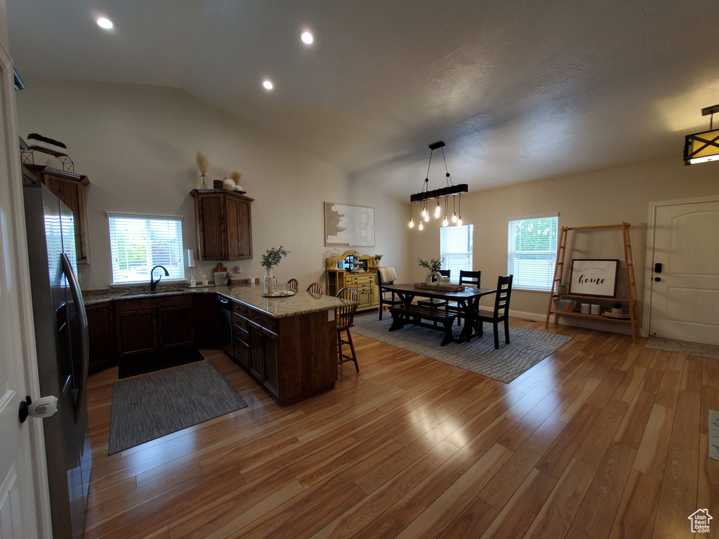 Kitchen with stainless steel fridge, a kitchen bar, a peninsula, a sink, and lofted ceiling
