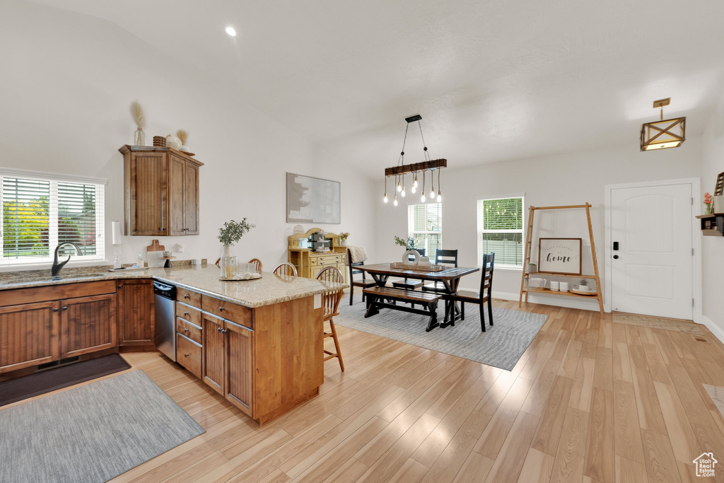 Kitchen with a sink, brown cabinetry, a peninsula, stainless steel dishwasher, and healthy amount of natural light