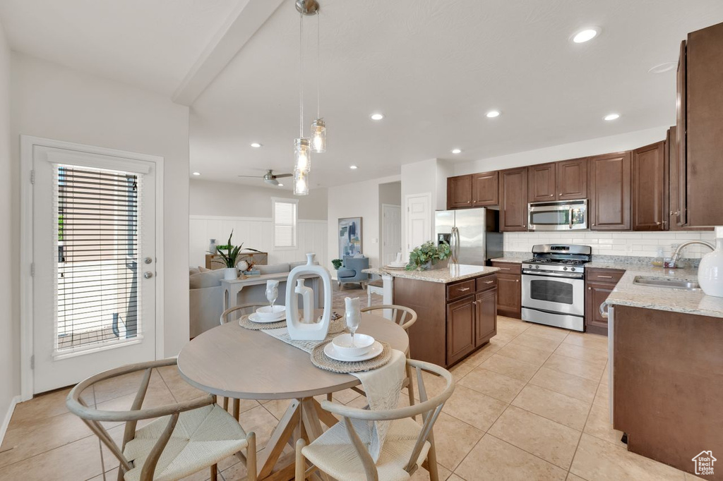 Kitchen featuring stainless steel appliances, a sink, a kitchen island, tasteful backsplash, and hanging light fixtures