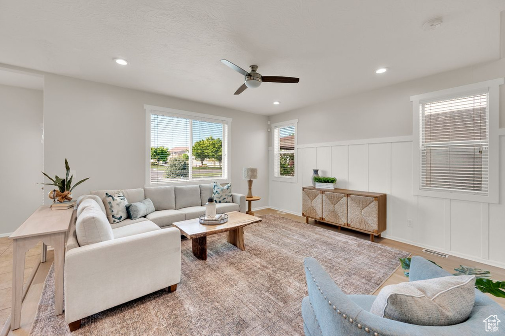 Living area with ceiling fan, recessed lighting, a decorative wall, wainscoting, and wood finished floors