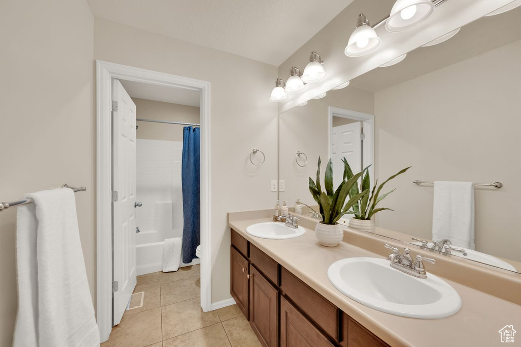 Full bathroom with tile patterned floors, double vanity, shower / bath combo, and baseboards