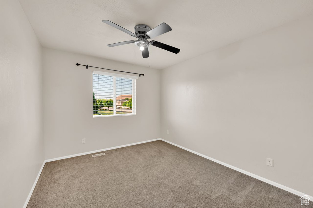 Spare room featuring carpet, baseboards, and a ceiling fan