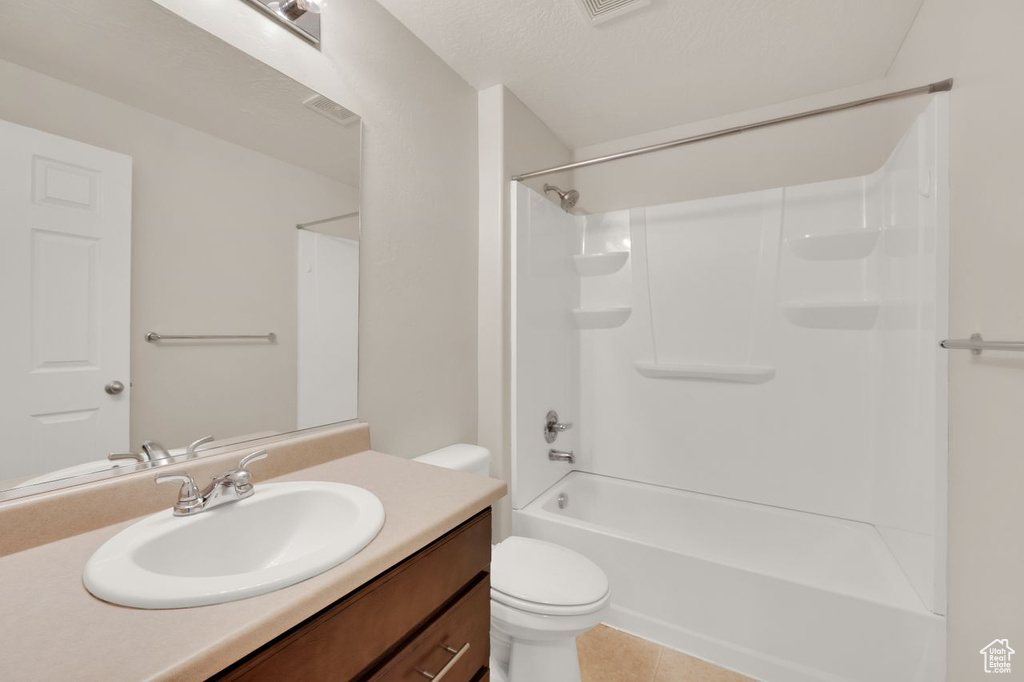 Full bath with toilet, vanity, tile patterned floors, and bathing tub / shower combination