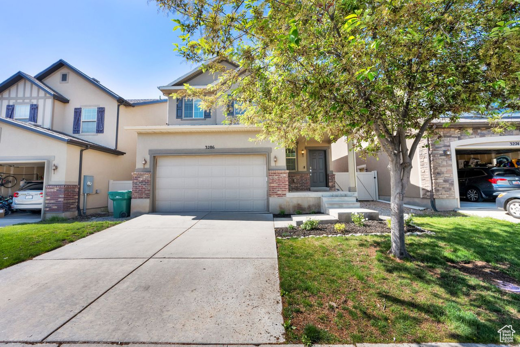 View of front of house with stucco siding, an attached garage, concrete driveway, and a front lawn