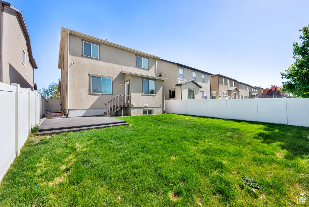 Rear view of property featuring stucco siding, a wooden deck, and a residential view