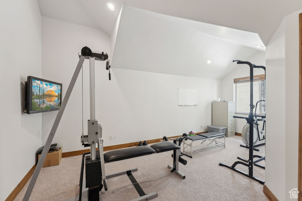 Exercise area featuring carpet flooring, lofted ceiling, and baseboards