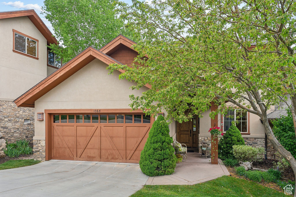 View of front of property featuring stone siding, stucco siding, a garage, and concrete driveway