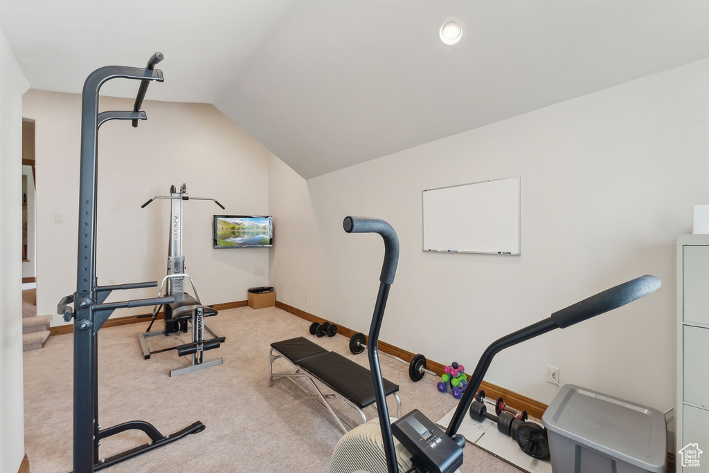 Workout room featuring lofted ceiling, light colored carpet, and baseboards