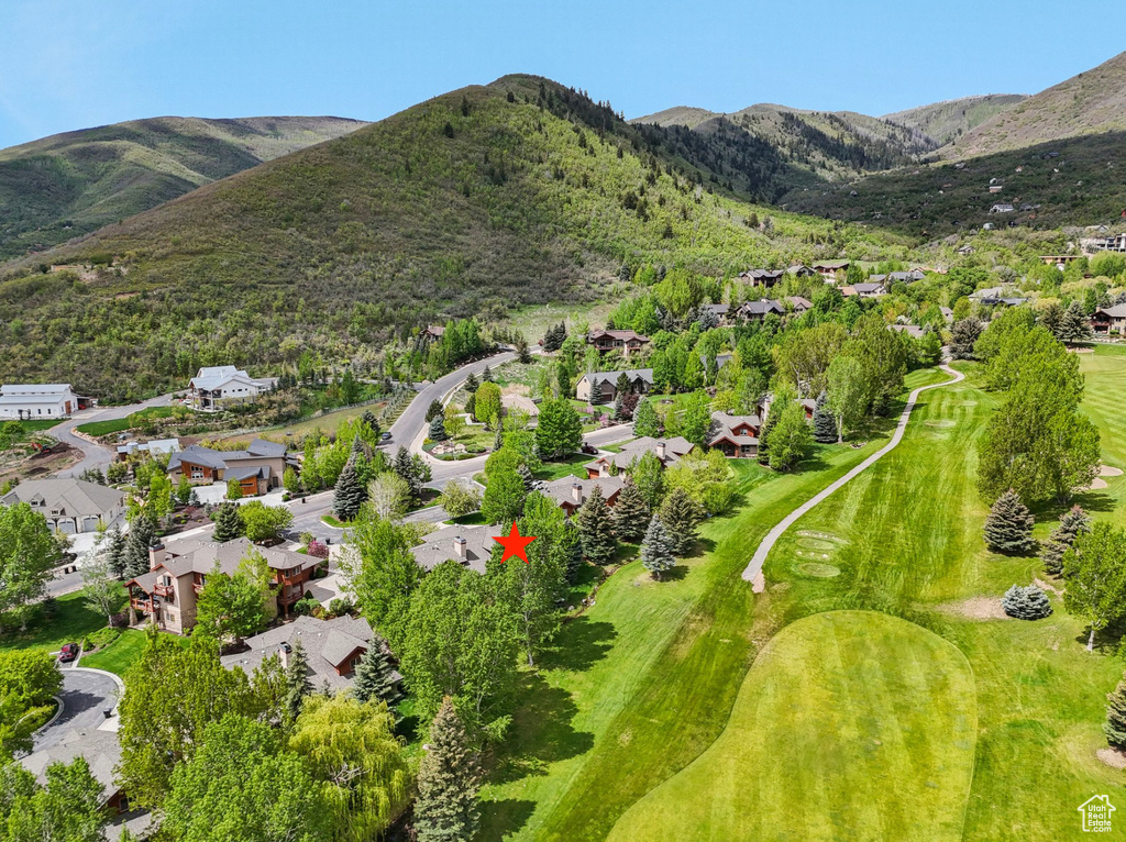 Aerial view of residential area featuring a mountainous background and a golf course
