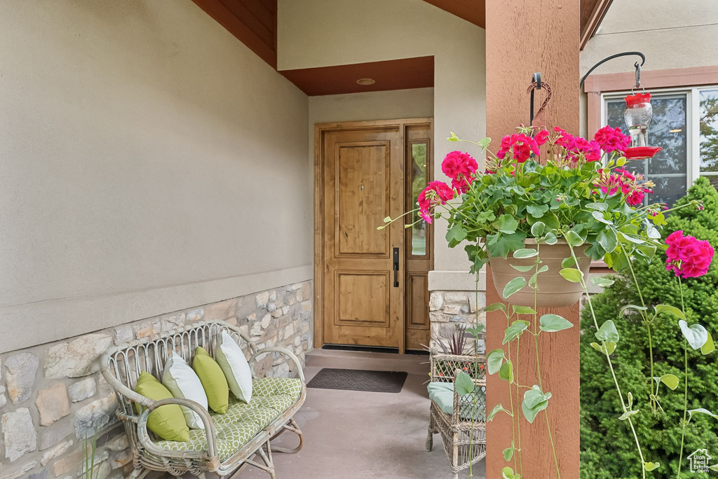 Property entrance with stucco siding, stone siding, and a porch