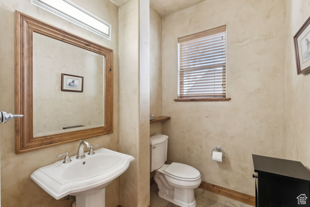 Half bathroom featuring toilet, a sink, and baseboards