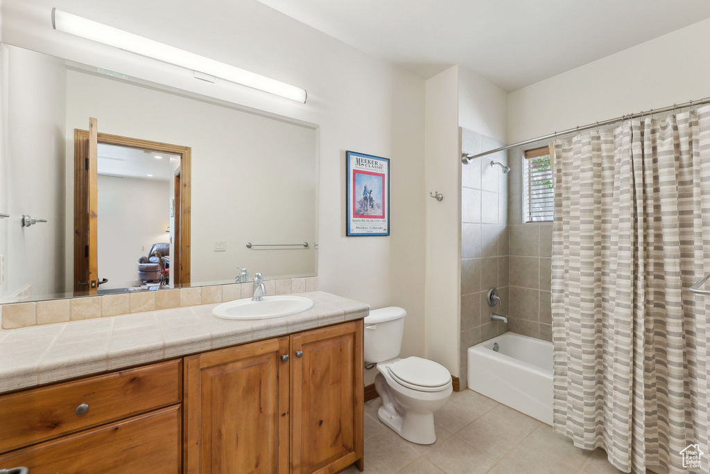 Bathroom featuring tile patterned floors, vanity, toilet, and shower / tub combo with curtain