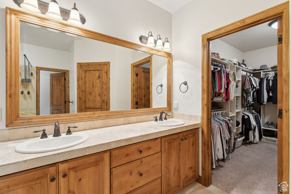 Full bathroom featuring double vanity and a spacious closet