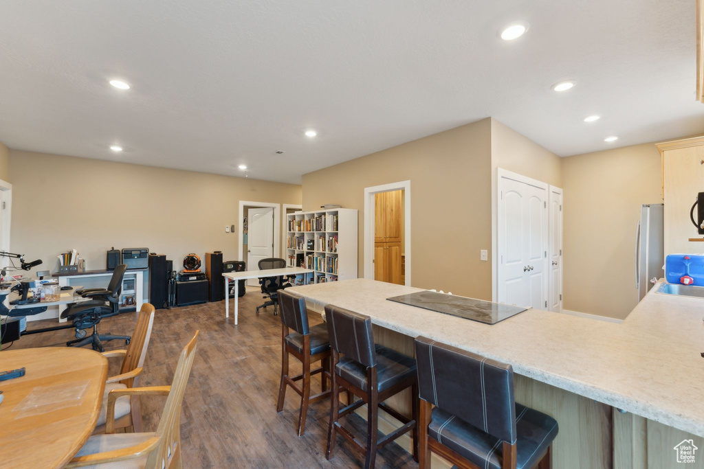 Kitchen featuring black electric stovetop, recessed lighting, a peninsula, dark wood-style flooring, and a breakfast bar area
