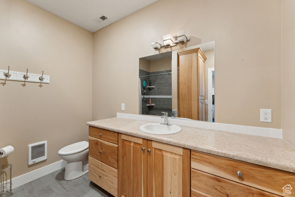 Bathroom with heating unit, toilet, vanity, a shower, and baseboards