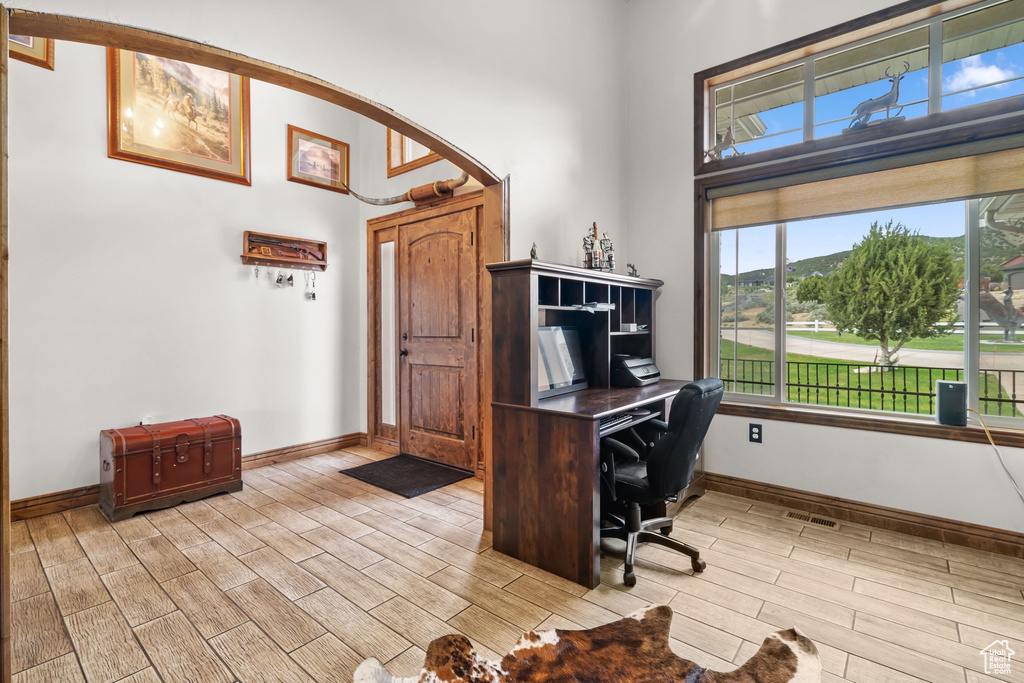Office area with a towering ceiling, wood tiled floors, arched walkways, and baseboards