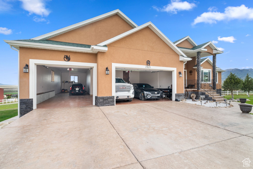 View of front facade with an attached garage, concrete driveway, stucco siding, and stone siding