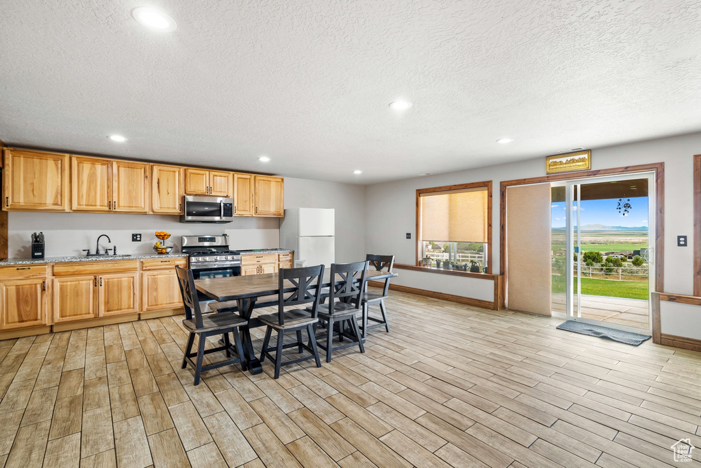 Dining area featuring a textured ceiling, recessed lighting, baseboards, and light wood-style floors