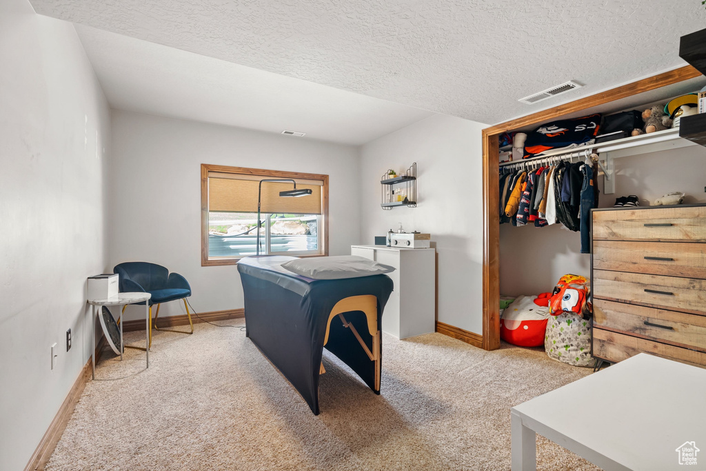 Bedroom with light carpet, baseboards, and a textured ceiling