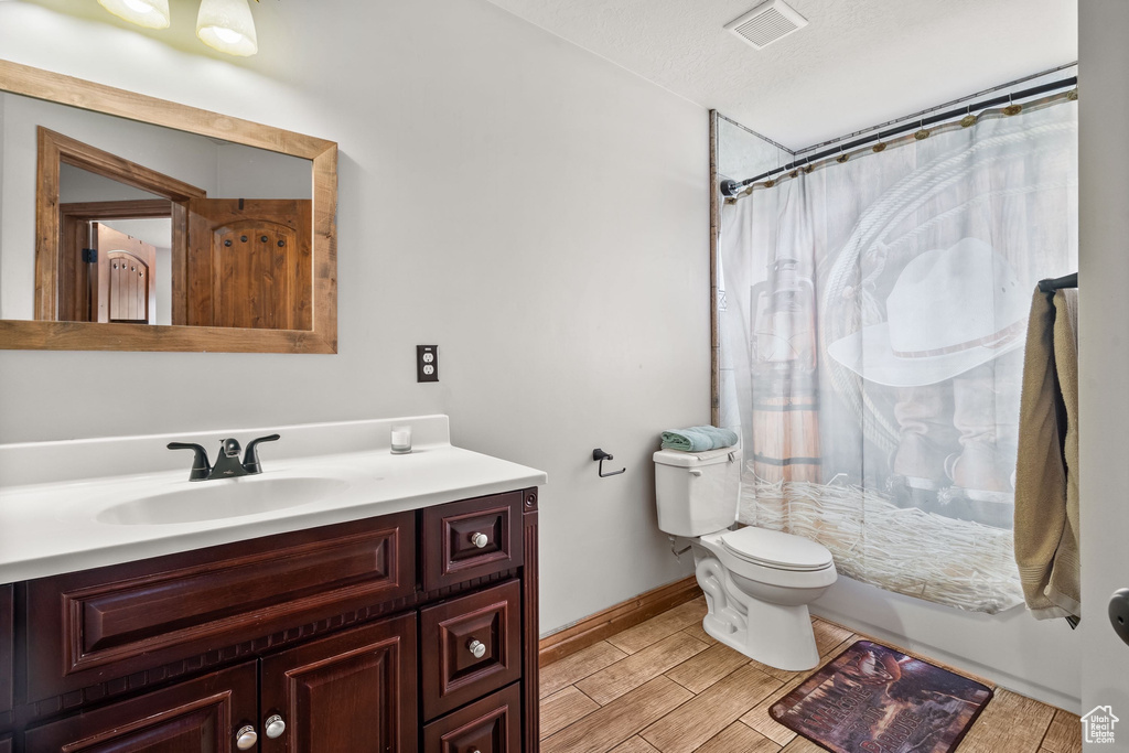 Bathroom featuring curtained shower, vanity, toilet, and baseboards