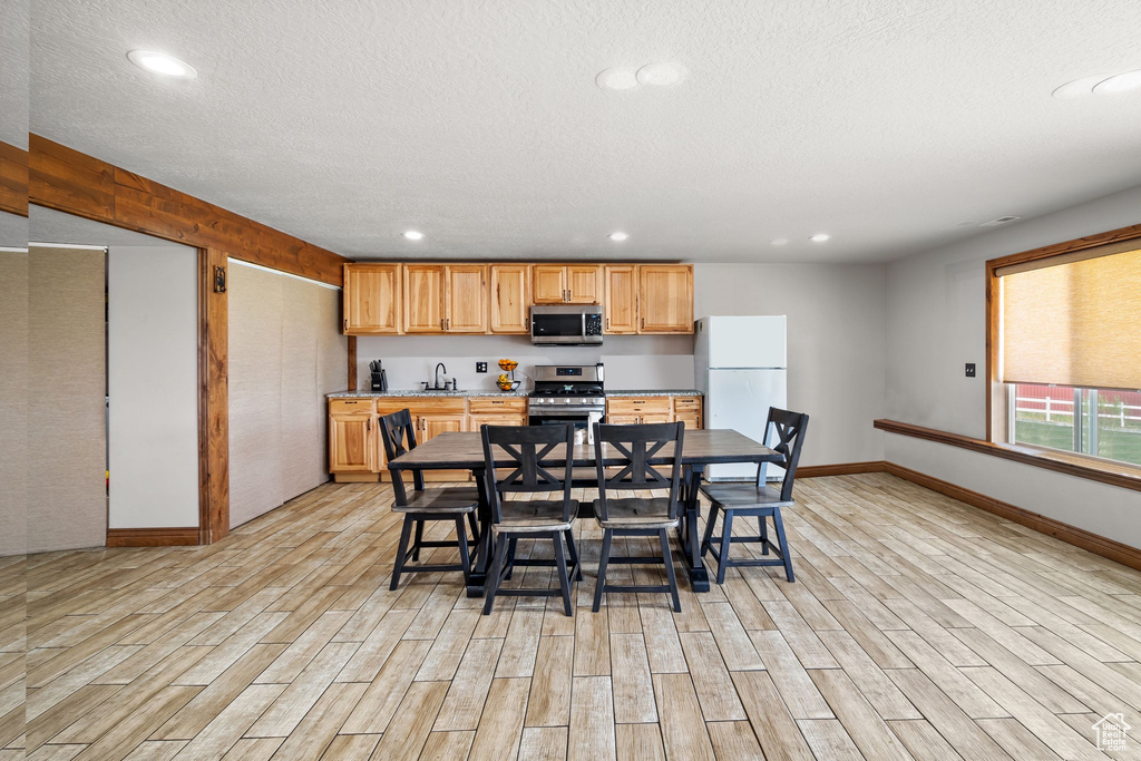 Dining area featuring light wood-style flooring, baseboards, recessed lighting, and a textured ceiling