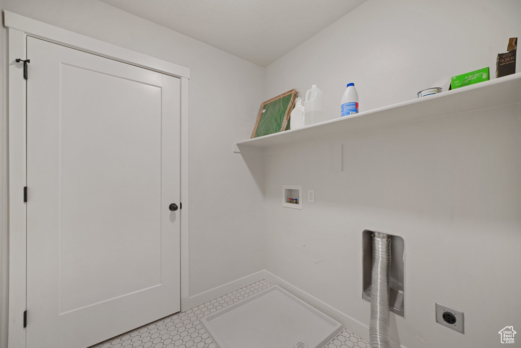 Washroom with electric dryer hookup, hookup for a washing machine, baseboards, and light floors