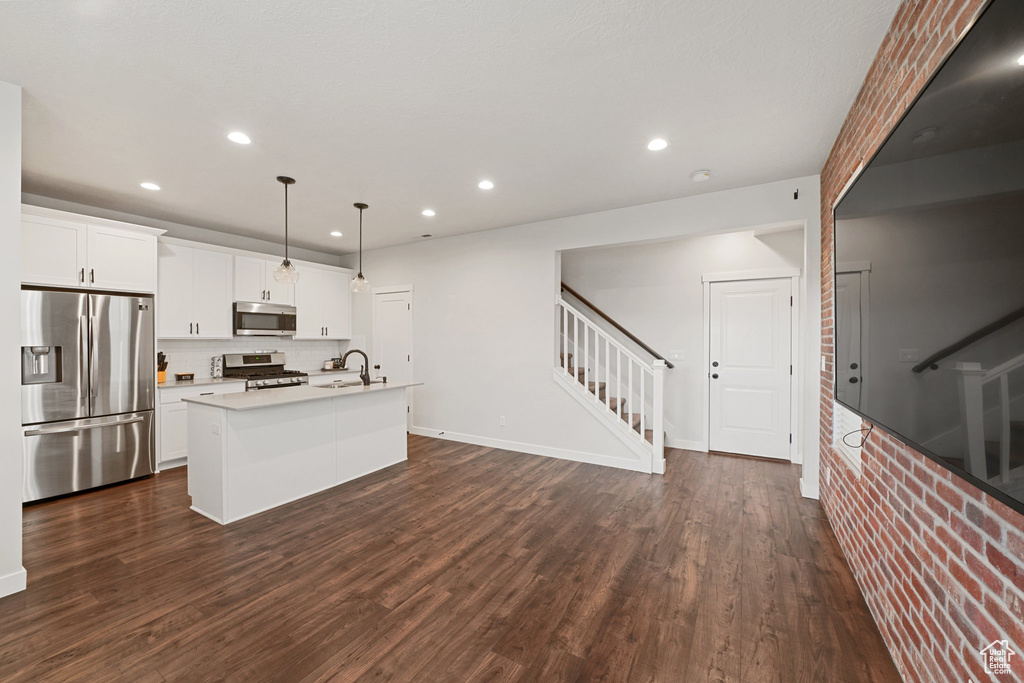 Kitchen featuring appliances with stainless steel finishes, recessed lighting, a center island with sink, a sink, and light countertops