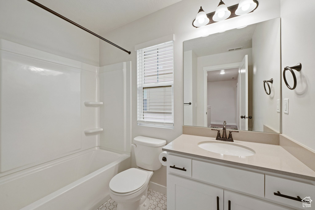 Full bath featuring toilet, vanity, baseboards, shower / bath combination, and tile patterned flooring