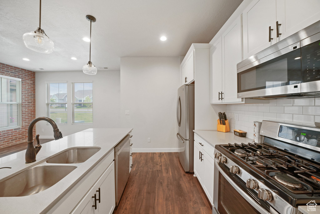 Kitchen with appliances with stainless steel finishes, a sink, decorative backsplash, dark wood-style floors, and recessed lighting