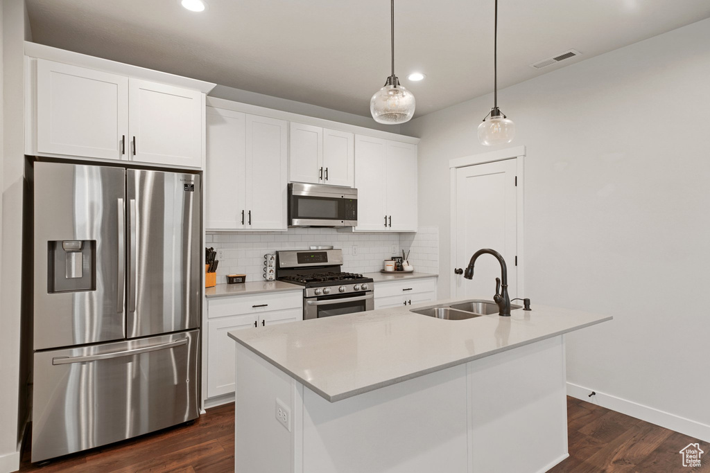 Kitchen featuring stainless steel appliances, a sink, backsplash, white cabinetry, and recessed lighting
