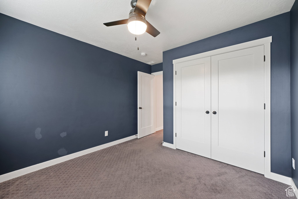 Unfurnished bedroom with carpet flooring, baseboards, a closet, and ceiling fan