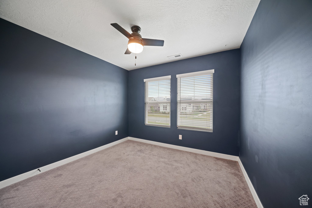 Spare room with a ceiling fan, carpet, baseboards, and a textured ceiling