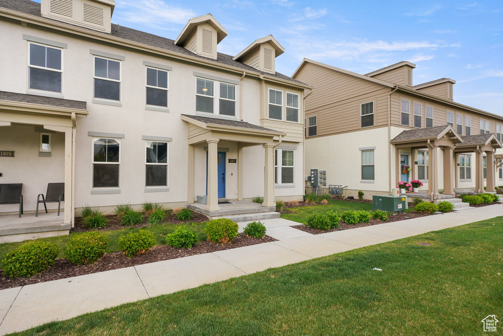 Townhome / multi-family property featuring a front yard and stucco siding