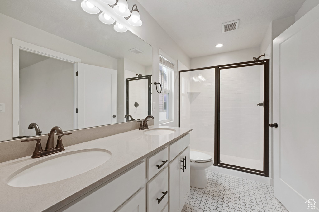 Bathroom with a shower stall, toilet, double vanity, and recessed lighting