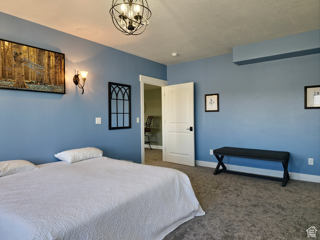 Carpeted bedroom with baseboards, a chandelier, and a textured ceiling
